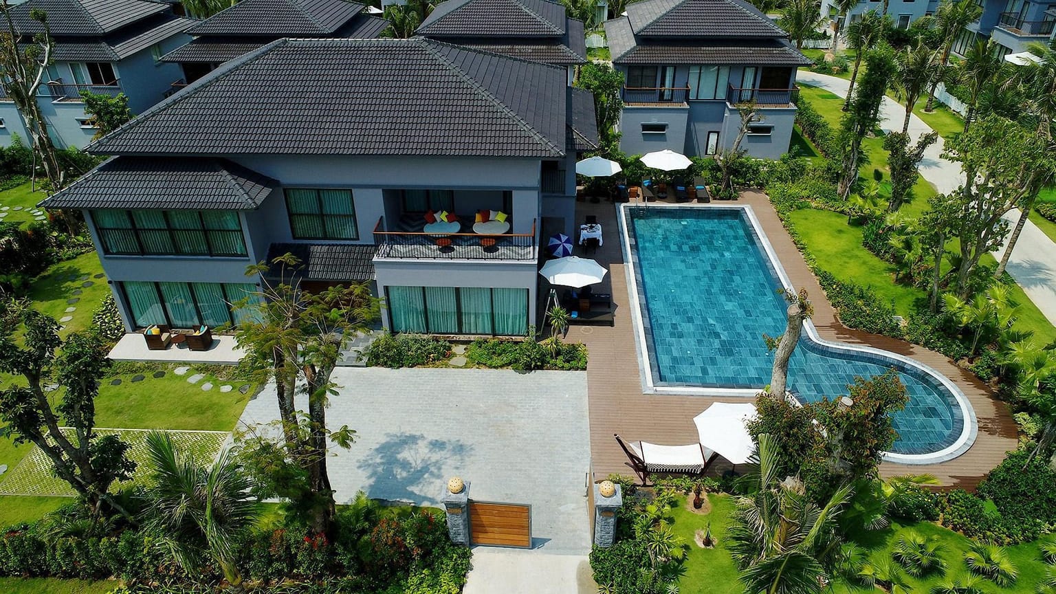 An aerial view of modern villas with private pools and lawns.